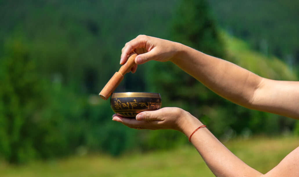 A woman holds a singing bowl in her hands. Selective focus. A woman holds a singing bowl in her hands. Selective focus. Nature.